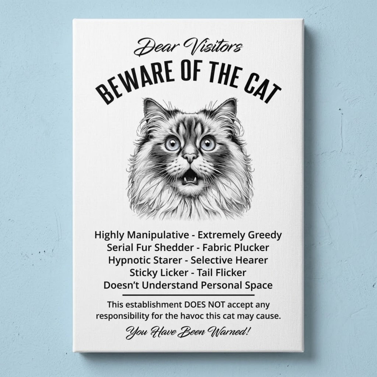 A rectangular white canvas sign with black printed funny text warning visitors about a Ragdoll cat, featuring a black-and-white illustration and humorous behavioral descriptions. The canvas print is photographed against a light blue wall.