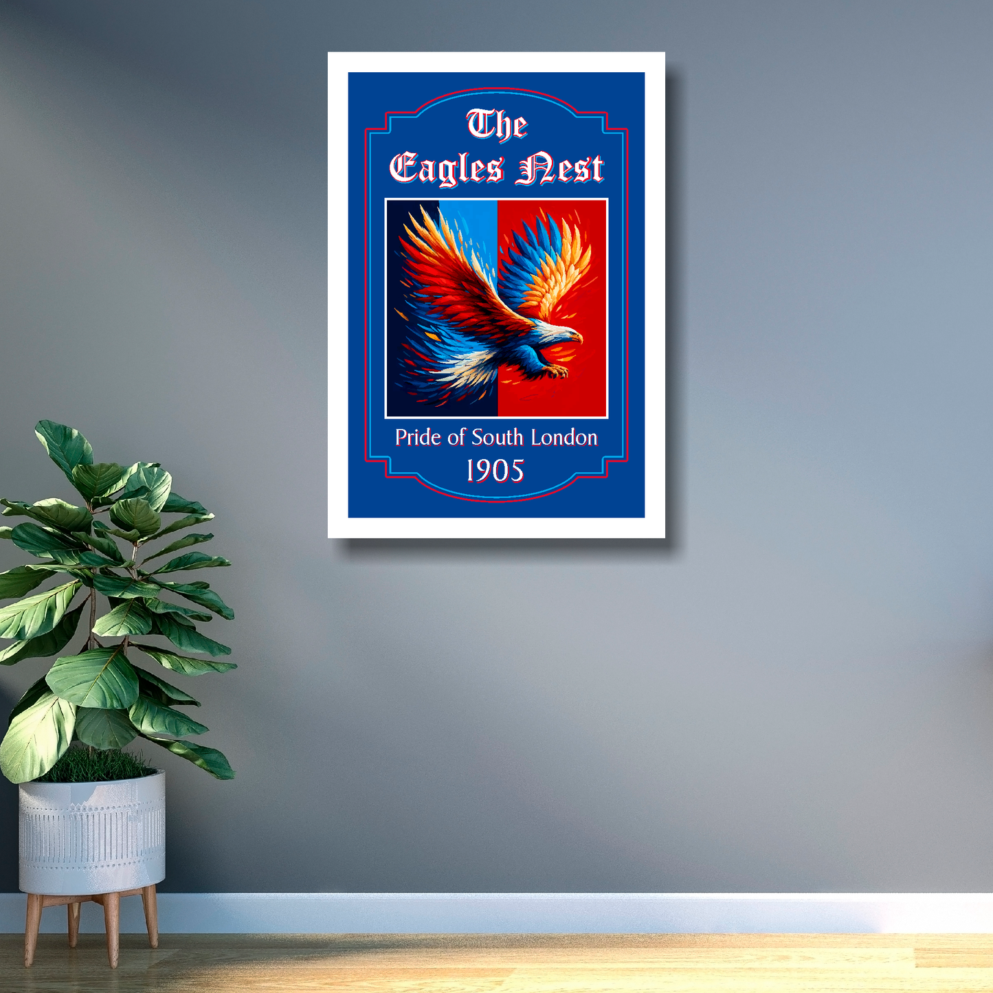 Framed artwork of an eagle with 'The Eagles Nest' text on a gray wall with a plant below.