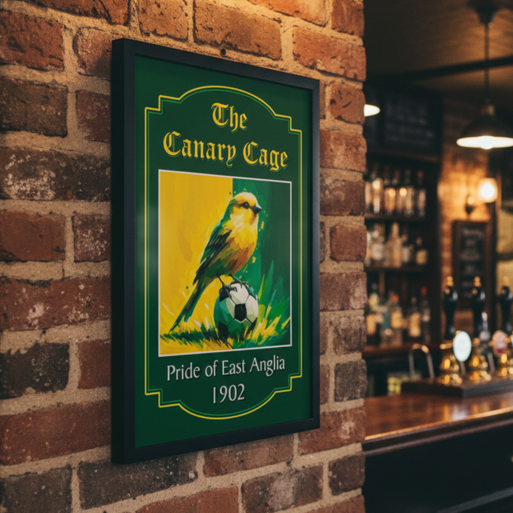 Black framed Norwich City FC art print 'The Canary Cage' text, displayed on a brick wall in a bar setting.