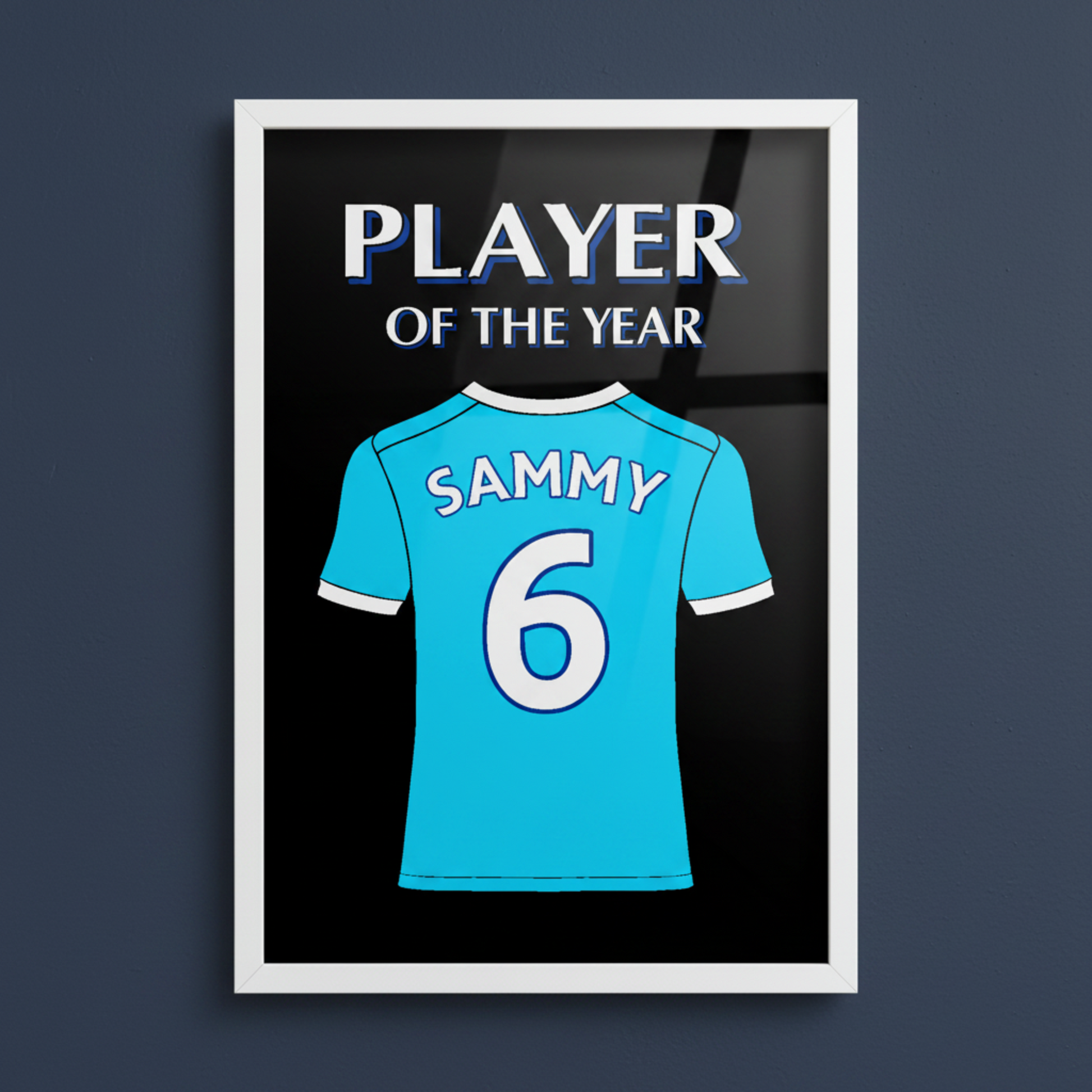 A framed art print featuring a Man City football shirt with 'SAMMY 6' on the back, above the words 'PLAYER OF THE YEAR' in white and blue, set against a black background with a white frame.