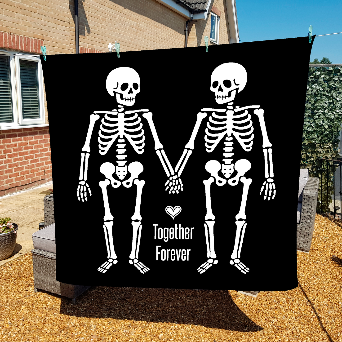 Skeleton couple holding hands with 'Together Forever' text on a black fleece blanket, hanging on washing line